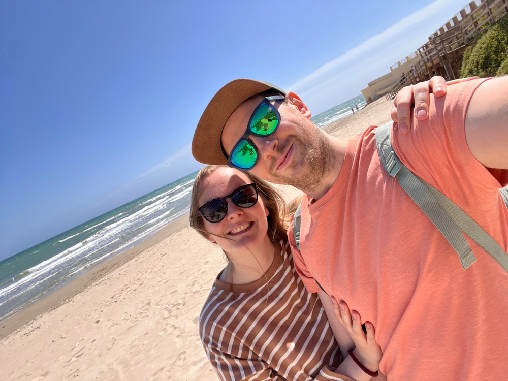 Camilla og Chris smiler mot kamera på stranden